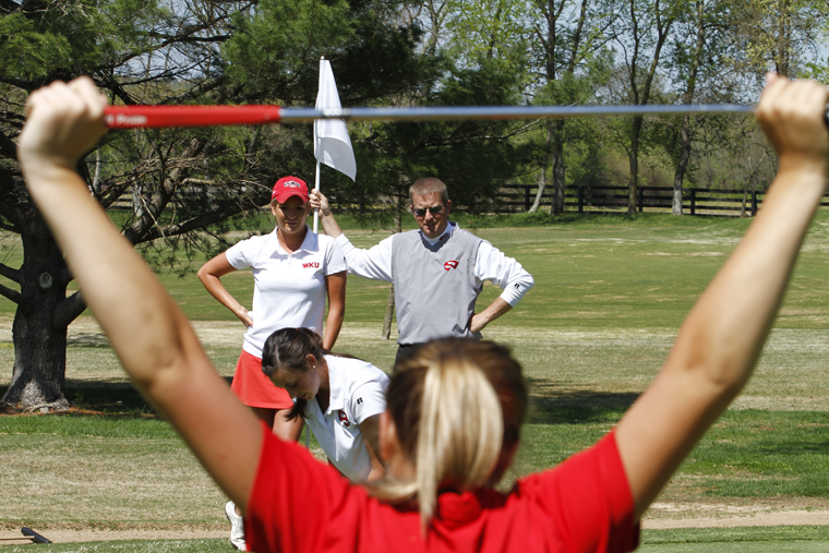 Sophomore Kelsey Burrell, senior JoAnna Smith, back left, and WKU head women’s golf coach Ron Burchett, back right, watch as sophomore Kristen Wilkinson putts Wednesday at the Bowling Green Country Club during practice. 