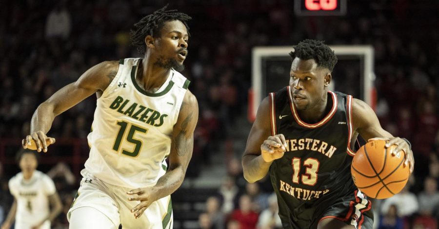 Sixth year guard Emmanuel Akot (13) drives down the court under heavy defense by UAB’s senior forward Ty Brewer (15) in E.A. Diddle Arena on Saturday, Feb. 25, 2023. WKU lost 72-60.