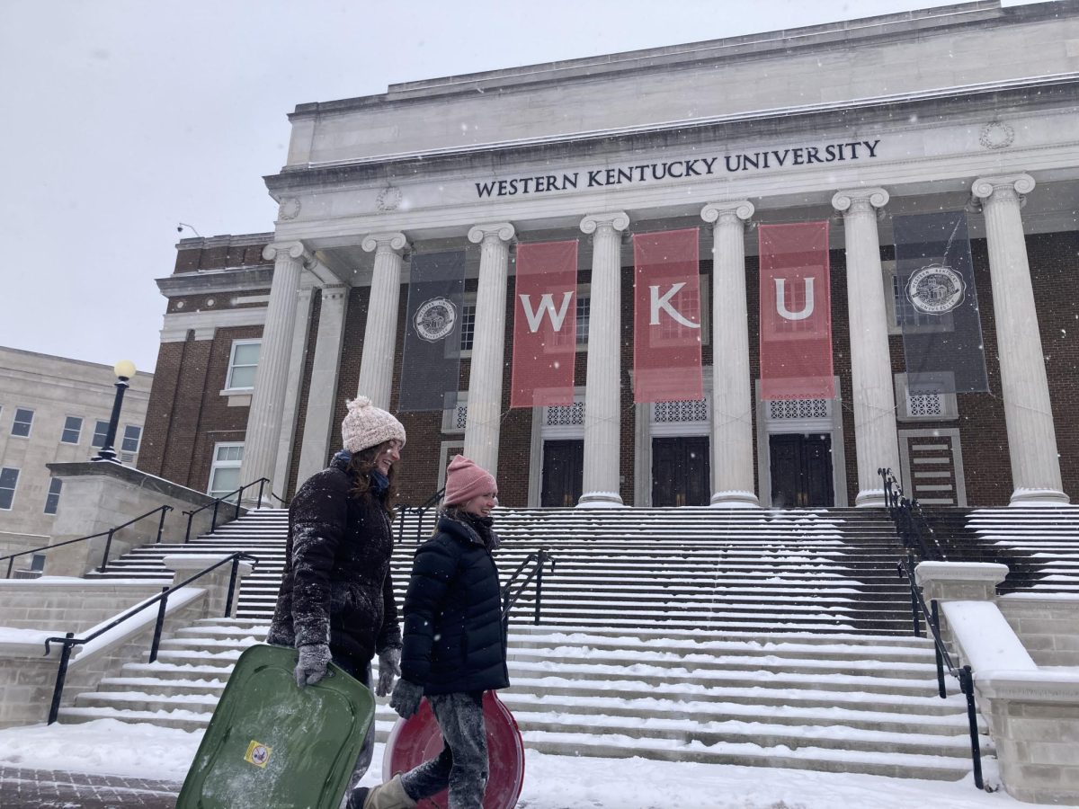 Olyvia Cool and Emma Durham walk past Van Meter Hall after sledding on WKU's campus on Jan. 15, 2024.