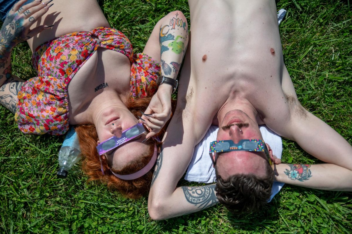 Adrianne Wallwork (left) and Trevor Angel look up at the sun during a total solar eclipse in Evansville, Ind. on Monday, April 8, 2024. The Evansville natives walked to the river front and were surprised at the amount of people there.