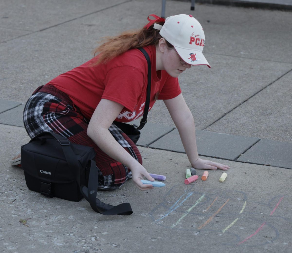 Kaylee Youngblood, a senior graphic design major decorates the concrete with chalk during the "We Stand With You" discussion in front of Cherry Hall on Wednesday, March 27, 2024