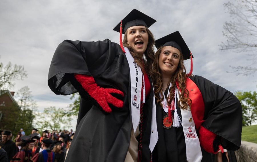 Graduating student(s) Kacy Weinburg (22, left) and Gianna Cecil (22, right) strike a pose in their graduation regalia before Topper Walk down Avenue of Champions on campus in Bowling Green, Ky. Both women sport red gloves to commemorate their time working as a team to help make the beloved campus mascot,“Big Red,” come to life. In order to embody the character, students must agree to keep their identity a secret until graduation. While Weinburg was the only one of the two to wear the suit, Cecil worked by her side acting as her “handler.”